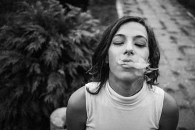 Beautiful young woman with eyes closed smoking 