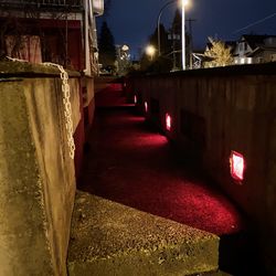 Illuminated street amidst buildings at night