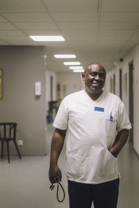 Portrait of smiling male doctor walking in hospital corridor