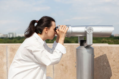 Side view of man photographing through binoculars