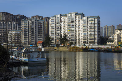 Boats moored in city against clear sky