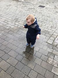 High angle view of boy standing on footpath during rainy season