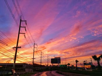 Cars on railroad tracks against sky during sunset