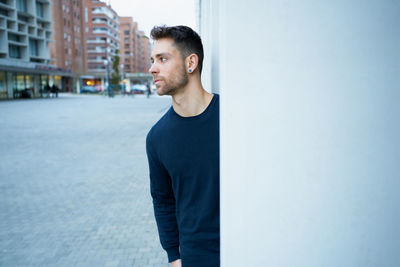 The modern man in casual clothes leaning against a wall