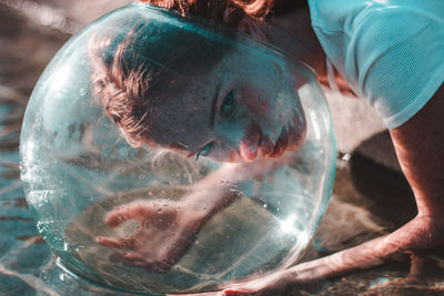 Close-up of woman wearing glass container at lake