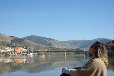 Woman by lake against clear sky