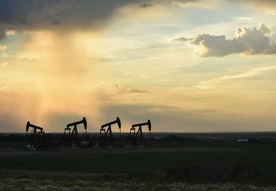 Silhouette people on field against sky during sunset