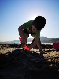 Boy playing with sand at beach