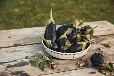 Different eggplants on dish and wooden table in the vegetable garden