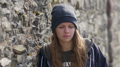 Portrait of beautiful young woman standing against wall