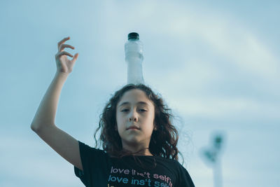 Portrait of young woman standing against sky
