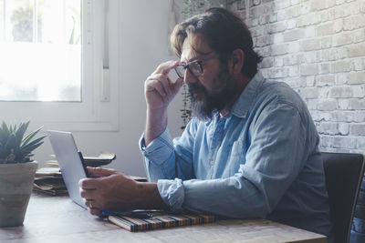 Young man using laptop while sitting on table