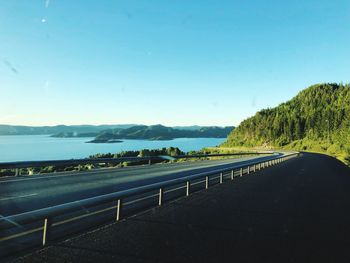 Road leading towards mountains against blue sky