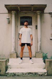 Full length portrait of young man standing against building