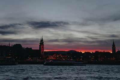 View of buildings at waterfront against cloudy sky