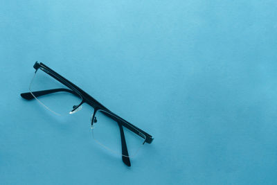 High angle view of eyeglasses on table against blue background