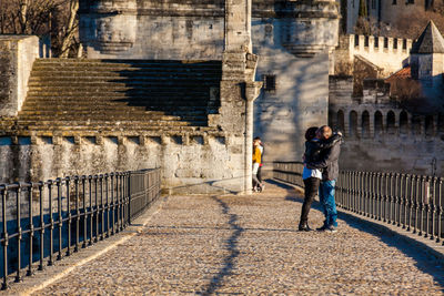 Full length of man standing on railing against buildings in city