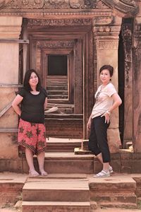 Full length of smiling women standing at entrance