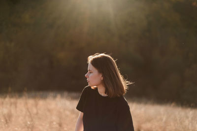 Woman looking away while standing on field