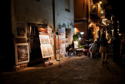 People walking on street amidst buildings at night