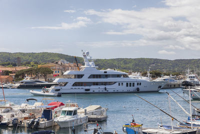 Boats moored at harbor against sky