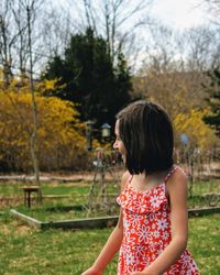 Girl looking at trees against sky