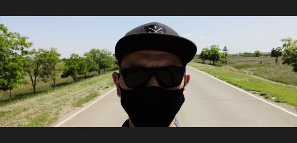 Portrait of man wearing sunglasses standing by road against sky