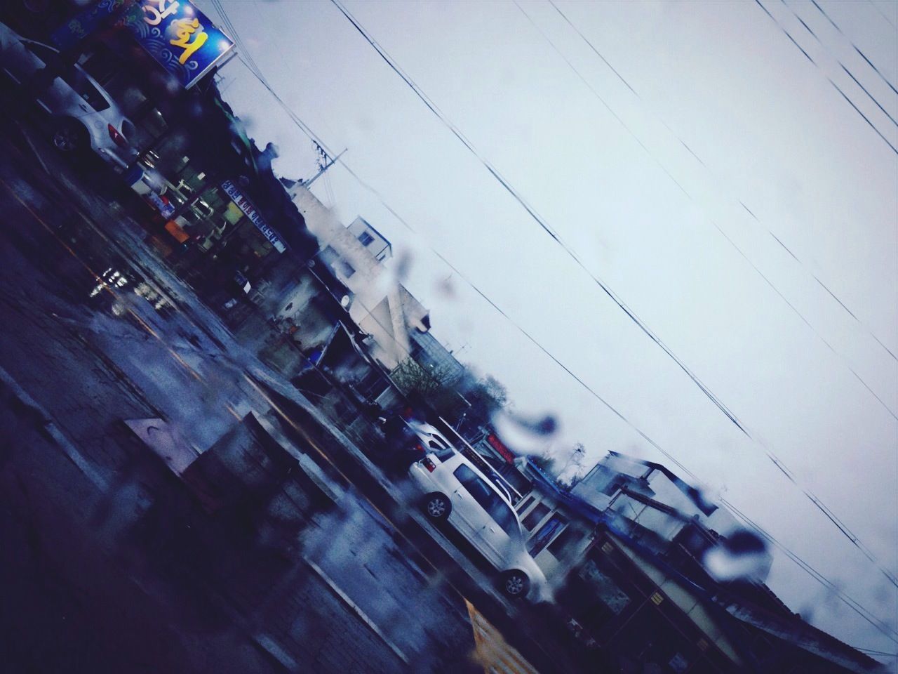 transportation, mode of transport, land vehicle, building exterior, car, city, architecture, built structure, street, power line, city life, city street, cable, high angle view, traffic, road, sky, electricity, travel, public transportation