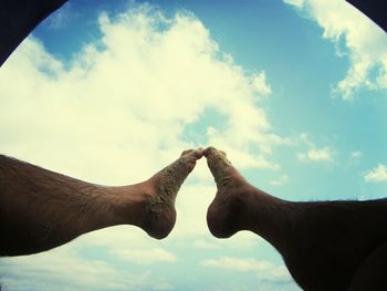 Low angle view of cropped hand against sky