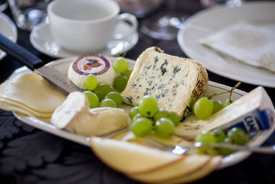 Close-up of cheese with grapes served on table