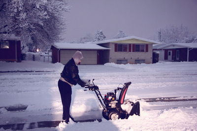 Side view of woman plowing snow with machinery