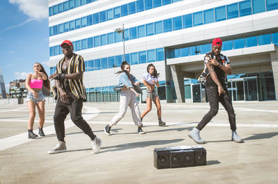 Friends dancing against building in city