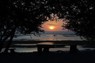 Silhouette trees by lake against sky during sunset