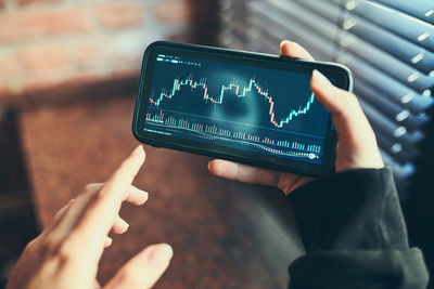 Person investing trading on stock cryptocurrency market using investing application on smartphone