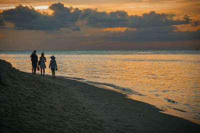 Silhouette of people walking at the beach against a golden sunset stone town, zanzibar