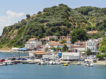 Sailboats moored on sea by buildings in city against sky