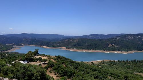 Scenic view of lake and mountains against clear blue sky