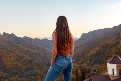 Rear view of woman looking at mountains against sky