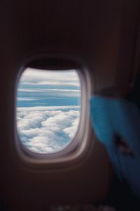 Reflection of clouds in sky seen through airplane window