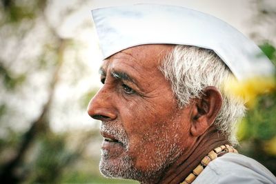 Side view of thoughtful senior man wearing white cap