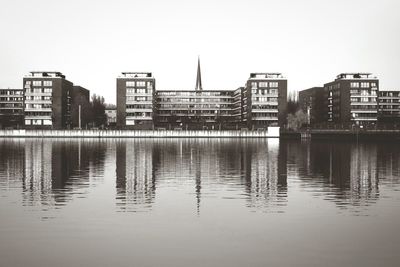 Reflection of buildings in river against clear sky