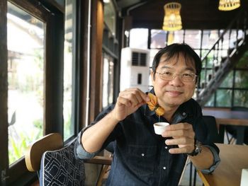 Portrait of mid adult man drinking glass in restaurant