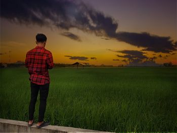 Man standing on field against sky during sunset