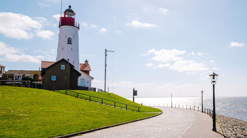 Lighthouse by sea against sky