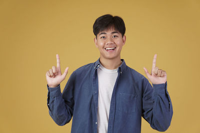 Portrait of teenage boy standing against yellow background