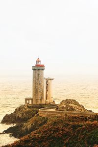 Lighthouse by sea against sky