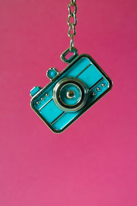 Close-up of camera hanging against pink background