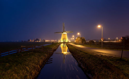 View of illuminated canal against clear sky at night