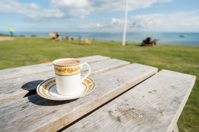 Close-up of coffee on table by sea against sky