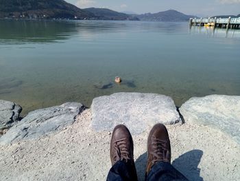 Low section of man against lake on rock